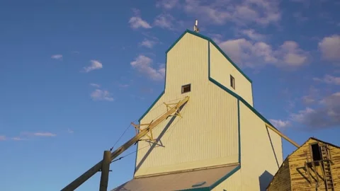 Low angle shot of a white grain elevator with setting sun rays falling on Vídeos de archivo 171579914