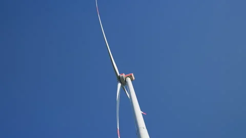 Low-Angle Shot of a Wind Turbine Spinning Against Blue Sky: 動画素材 338185388