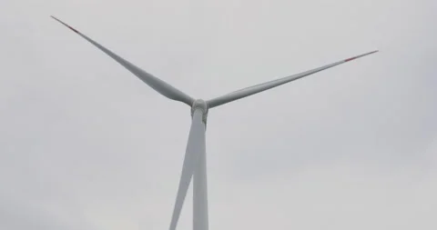 Low angle shot of a windmill against a grey, dull and cloudy sky. Green Energy Stock Footage 160353489