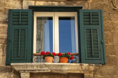 Low angle shot of a window with shutters and beautiful flowers. 스톡 사진