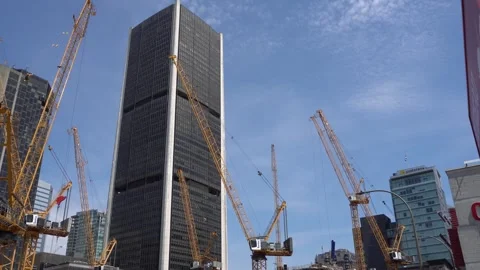 Low angle shot of yellow lattice boom cranes operating at a city construction Video stock 335306441