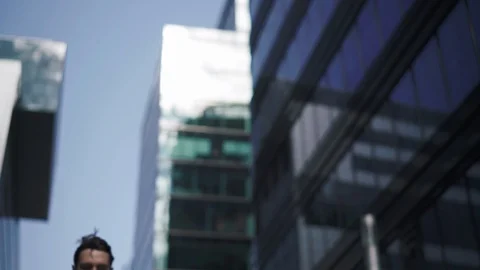 Low angle shot of young man talking on phone holding coffee cup outdoors Stock Footage 95588225