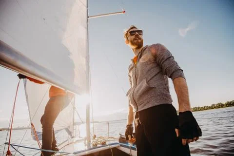 Low angle shot of a young man sailor wearing sunglasses and gloves on a sailing Stock Photos