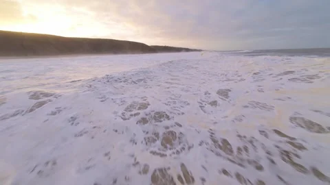 Low-angle shots capture seafoam rolling toward shore Video stock 344672549