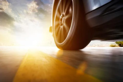 Low angle side view of car driving fast at sunset with motion speed effect . Stock Photos