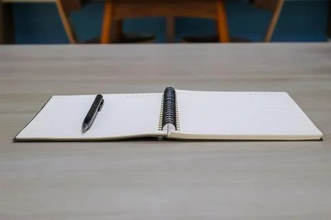 Low angle side view. Lined notebook page with pen on wooden table background. Stock Photos