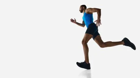 Low angle side view of muscular man, runner in motion, running, training Stock Photos