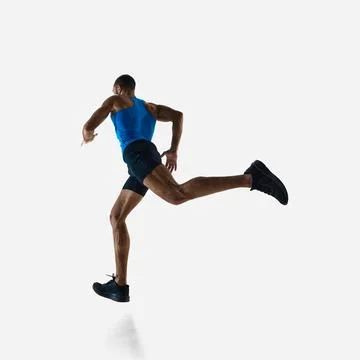 Low angle side view of muscular man, runner in motion, running, training Stock Photos