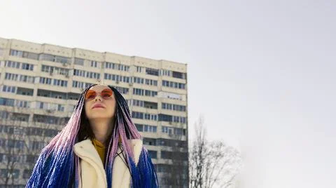 Low angle side view of young female in warm clothes and trendy sunglasses sta Stock Photos