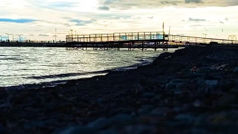 Low Angle Silhouette of Pier with Waves Breaking on the Shore at Sunset Stock Footage 323139950