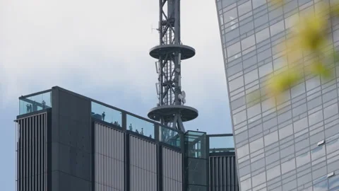 Low angle skyscraper rooftop observation deck with people behind glass Video stock 333651146