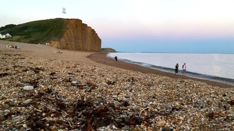 Low angle slide shot of the beach and cliffs in West Bay Stock Footage 94364345