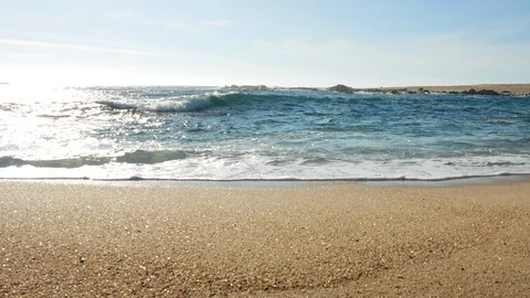 Low angle slider shot along beach parallel to shoreline on sunny summer day Stock Footage 108515161