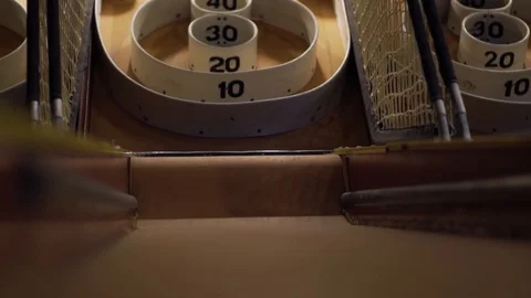 Low angle slo-motion shot of a skee-ball ramp as a skee-ball zooms down it. Stock Footage 93239409