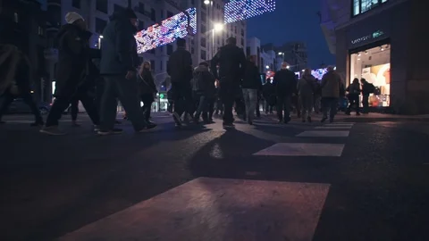 Low angle slow motion following crowds across road &amp; sidewalks in shopping Stock Footage 102472742