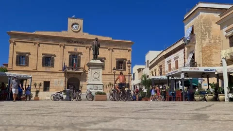 Low-angle slow motion of man on bicycle at europa square, favignana Stock Footage 280890254