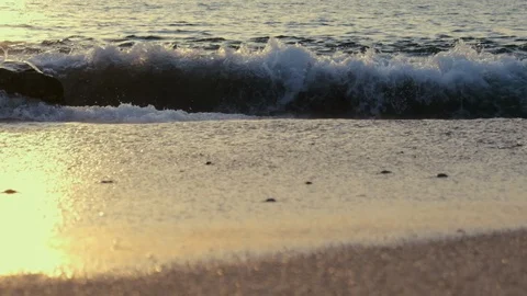 Low angle, slow motion tracking shot along beach at sunset Stock Footage 115996301