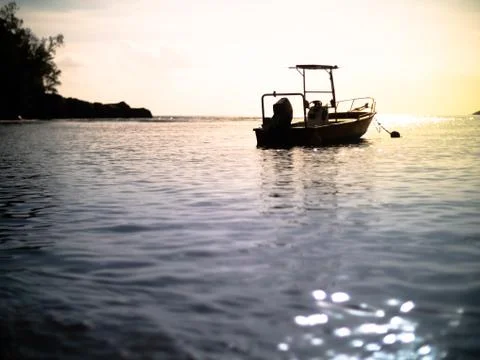 Low angle of a small anchored motor boat silhouetted during a Seychelles suns Foto stock