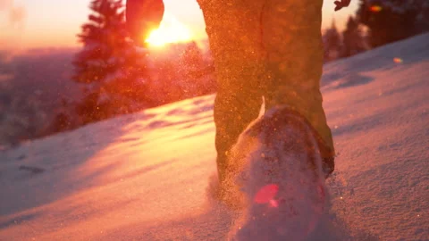 LOW ANGLE: Snowflakes glisten as man runs along the snowy meadow at sunset. Stock Footage 147140547