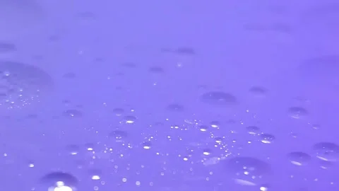 Low angle spinning and settling oil bubbles wallpaper macro in lavender Video stock 301667250