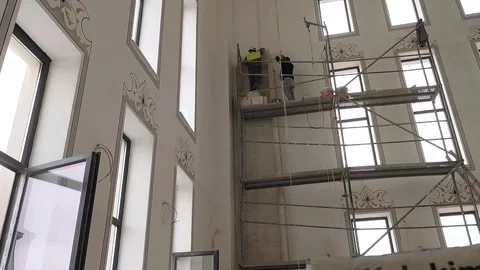 Low-angle static interior shot of construction workers on a high scaffolding Vídeos de archivo 335997954