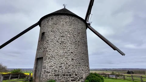 Low angle static shot of a historic stone windmill under a dramatic overcast sky Stockbeeldmateriaal 332679433