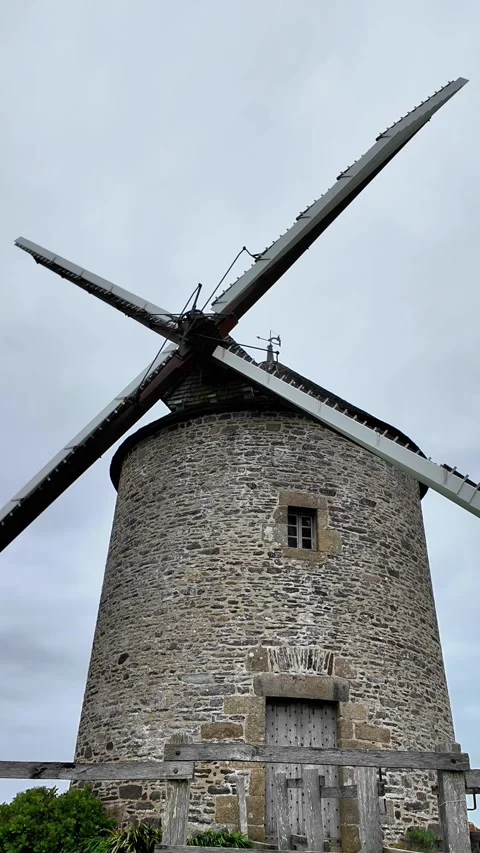 Low angle static shot of a historic stone windmill under a dramatic overcast sky Vídeos de archivo 332679434