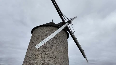 Low angle static shot of a historic stone windmill under a dramatic overcast sky Vídeos de archivo 332679441