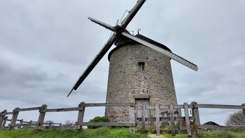Low angle static shot of a historic stone windmill under a dramatic overcast sky Vídeos de archivo 332679463