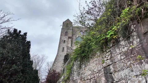Low angle static shot of the Mont Saint-Michel Abbey towering over traditional s Vídeos de archivo 332724035