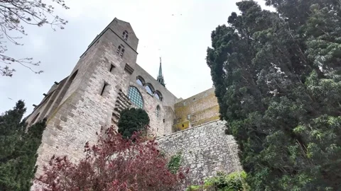 Low angle static shot of the Mont Saint-Michel Abbey towering over traditional s Vídeos de archivo 332724037