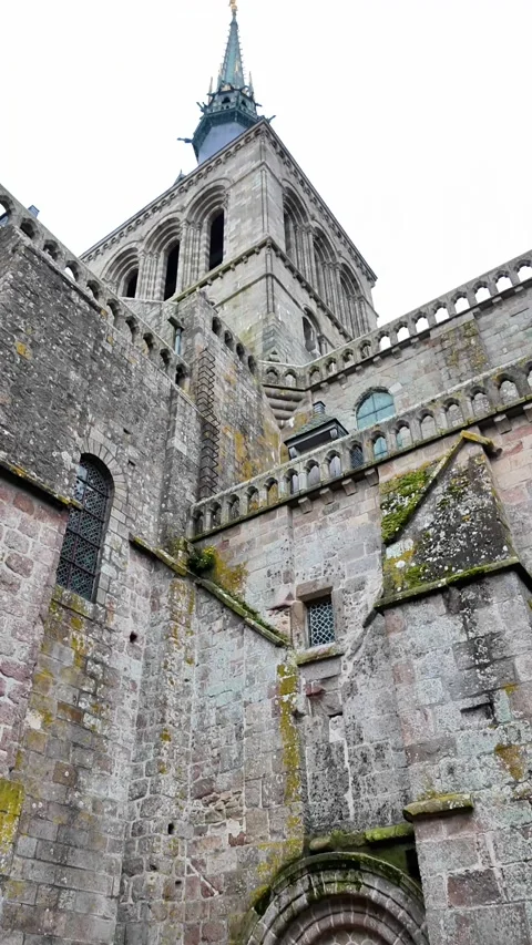 Low angle static shot of the Mont Saint-Michel Abbey towering over traditional s Vídeos de archivo 332724062