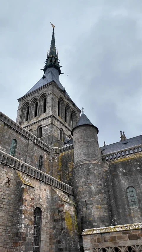 Low angle static shot of the Mont Saint-Michel Abbey towering over traditional s Vídeos de archivo 332724107