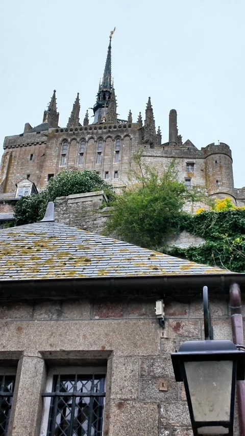 Low angle static shot of the Mont Saint-Michel Abbey towering over traditional s Vídeos de archivo 332724164