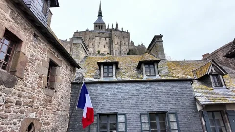 Low angle static shot of the Mont Saint-Michel Abbey towering over traditional s Vídeos de archivo 332724178