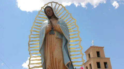 Low Angle of a Statue of the Virgin Guadalupe with an Adobe Catholic Church Stock Footage 64835066