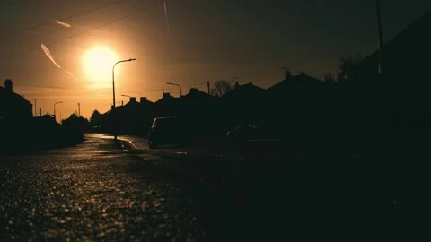 Low angle sunlight reflecting on textured asphalt with driving car in foreground Stock Footage 311523926
