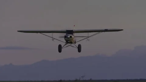 Low angle of Super Cub plane flying close to the ground and passing over camera Stock Footage 252383055