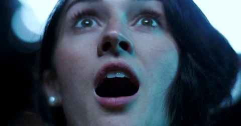 Low angle, a surprised look on a young woman's face as she watches a movie Stock Footage