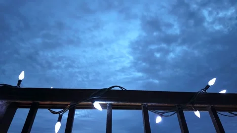Low angle time-lapse of a balcony railing with illuminated string lights at dusk Stock Footage 294951292