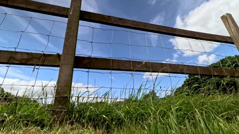 Low Angle Timelapse of Wooden Field Fence and Grass Under Fast Moving Clouds Stock Footage 340857197