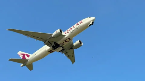 Low angle tracking shot of a Qatar Cargo airplane flying overhead against a Stock Footage 347363432