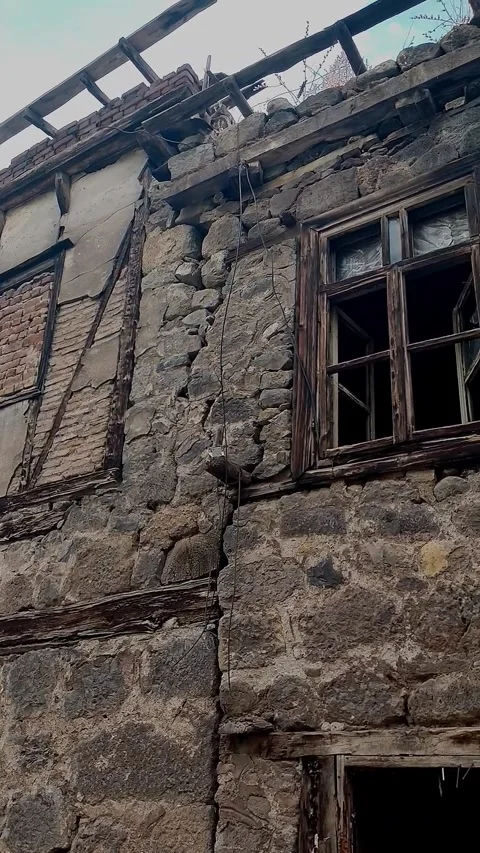 Low angle tracking shot of a ruined stone house with collapsed roof and expo 動画素材 328402243