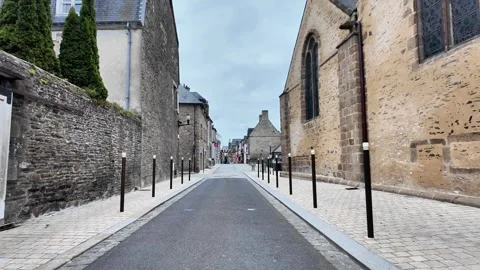 Low-angle tracking shot through a clean, modern cobblestone street in a French t Vidéo 332804018