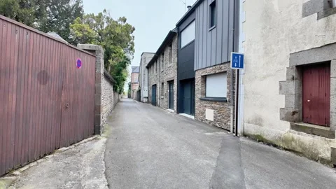 Low-angle tracking shot through a narrow, modern-meets-traditional alleyway in a Vídeos de archivo 332804151