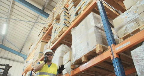 Low angle tracking shot of a worker in a warehouse talking on the phone Stock Footage 65041254