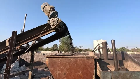 Low angle tracking view capturing raw dark aggregate material pouring from the Stock Footage 337630665