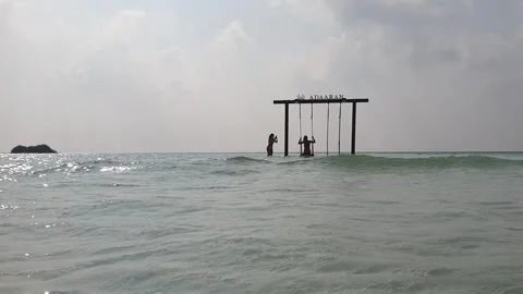 Low angle of two female tourists taking pictures on water swing in maldives Stock Footage 280795253