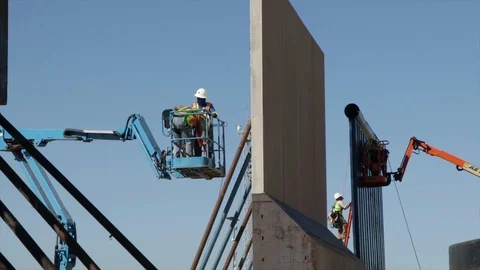 Low angle of two men in a telehandler working in The Trump's Wall Stock Footage 99043888
