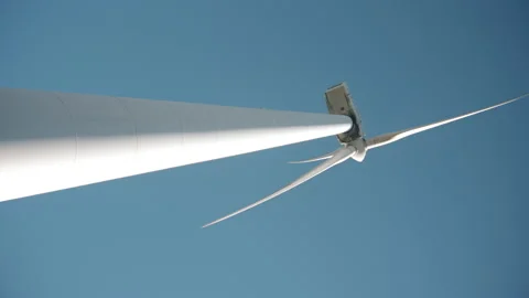 Low angle vertical footage of a wind mill against pale blue sky.   Video stock 170667656